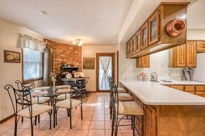 A kitchen with a large island, wooden cabinets, and a brick wall. - Dragonfly Estate - the Main House & Studio (South Fork)