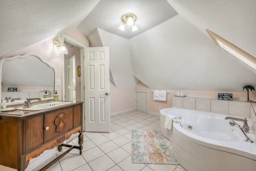 A bathroom with a vanity, sink, mirror, and bathtub.