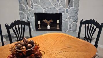 Un coin repas avec une cheminée en pierre, une table en bois et deux chaises.
