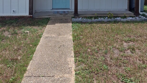 A single-story house with a front door, a small porch, and a window with a flower box.