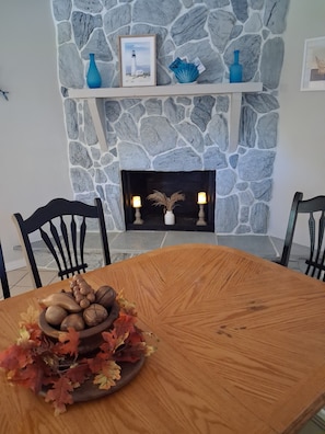 A dining area with a stone fireplace, a wooden table, and chairs.