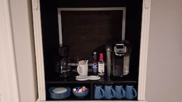 A white cabinet with drawers, a coffee maker, and a microwave on top.