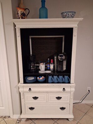 A white cabinet with drawers, a coffee maker, and a microwave on top.