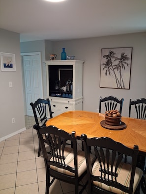 A dining area with a wooden table and chairs, a white cabinet, and a framed picture on the wall.