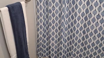 A bathroom with a patterned shower curtain, a white toilet, and a dark blue towel on a rack.