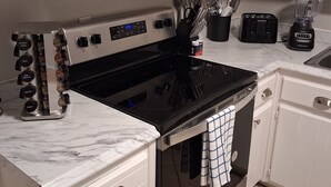 A kitchen with white cabinets, a black stove, a toaster, and a blender on the countertop.