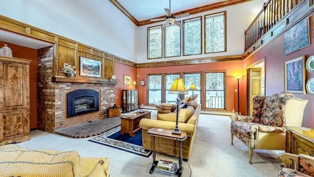 A spacious living room with a fireplace, comfortable seating, and large windows. - The Dragonfly Main House (South Fork)