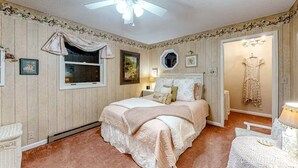 A bedroom with a bed, a ceiling fan, a window, and a door leading to another room. - The Dragonfly Main House (South Fork)