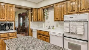 A kitchen with wooden cabinets, granite countertops, a refrigerator, and a dishwasher. - The Dragonfly Main House (South Fork)