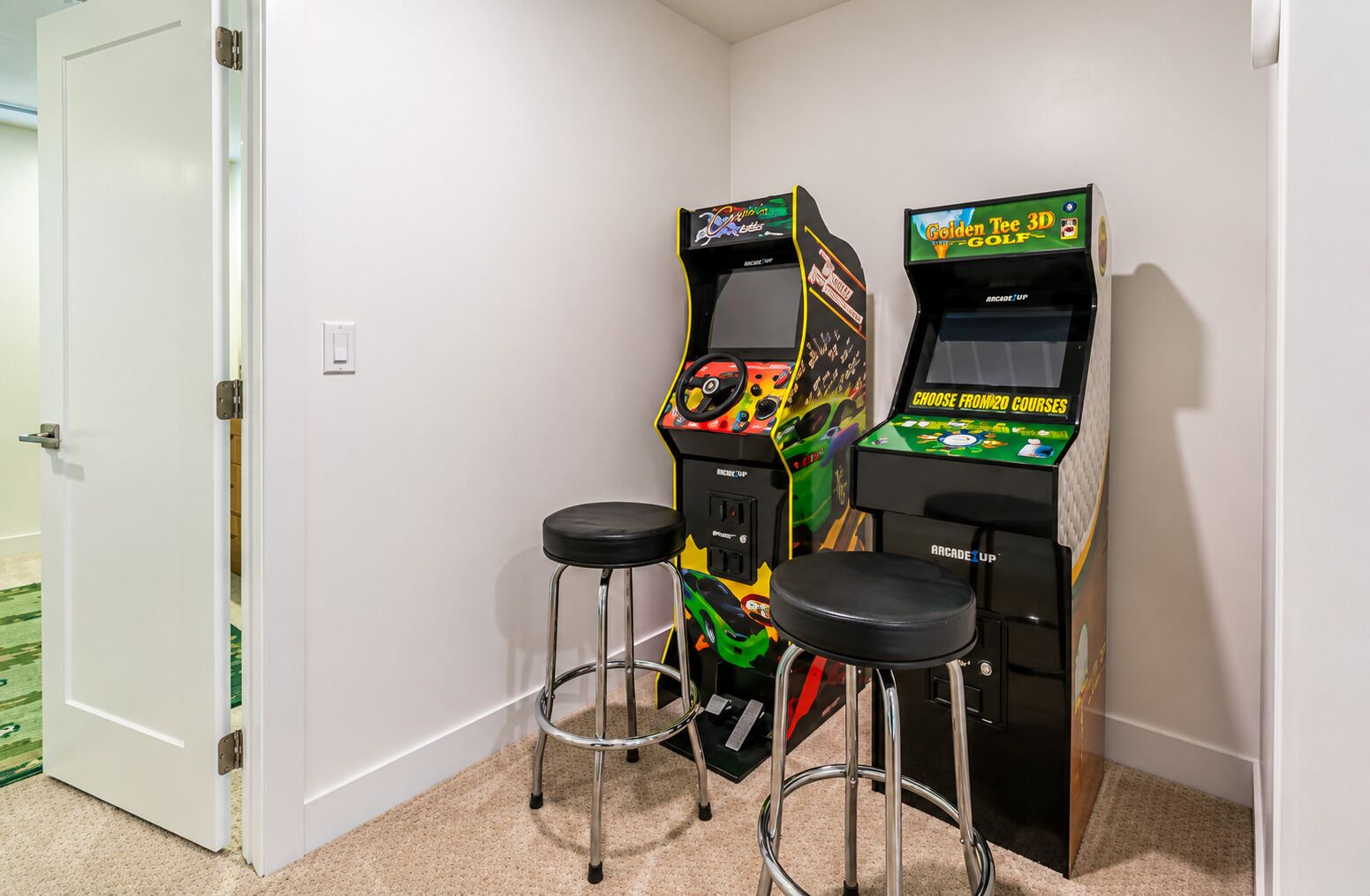 Two arcade machines, a door, and two stools in a room.