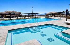 Una piscina con trampolín, sillas de descanso y vistas a montañas.