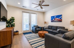 Ein modernes Wohnzimmer mit Ecksofa, Couchtisch und Deckenventilator.