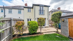 A two-story residential building with a patio area, a wooden fence, and a small garden. - Cosy 3BR House with free parking (Oxford)