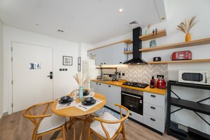 Een compacte keuken met moderne apparaten, een eettafel met stoelen en een klein keukenblok.