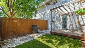 Ein Garten mit Holzterrasse, Grill und Glashaube.