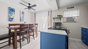 Eine moderne Küche mit Mikrowelle, Deckenventilator und einem Fenster mit Jalousien.