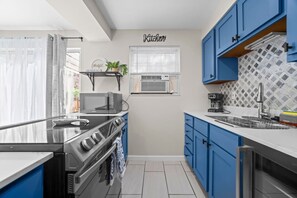 Een moderne keuken met een fornuis, magnetron en blauwe kastjes.