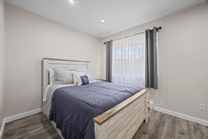 Un dormitorio con una cama de madera, una mesita de noche y una ventana con cortinas.