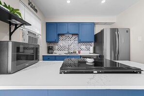 Una cocina moderna con armarios azules, un refrigerador de acero inoxidable, un horno empotrado y una encimera con un tazón.