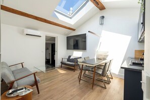 Ein zeitgemäßer Wohnraum mit Oberlicht, Flachbildfernseher, Essbereich und Küche.