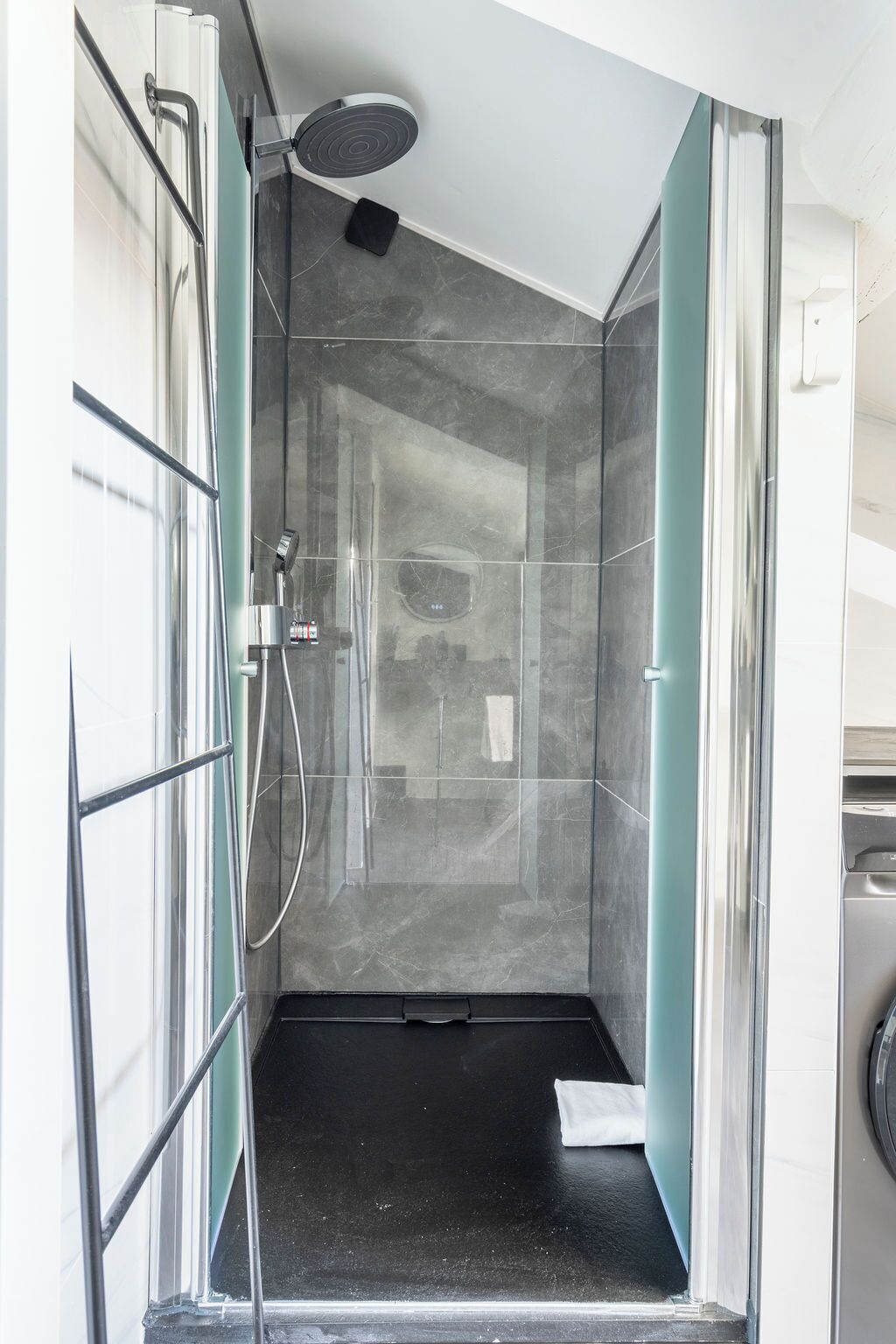 A modern shower with a glass enclosure, a handheld showerhead, and a built-in seat.