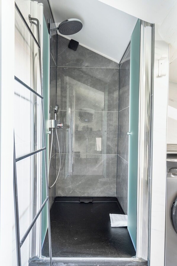 Eine moderne Dusche mit Glastrennwand, Duschbrause für die Hand und integrierter Sitzgelegenheit.