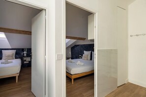A bedroom with a bed, a nightstand, a lamp, and a window. - La Mansarde du Bivouac, cocon sous les toits (Cannes)
