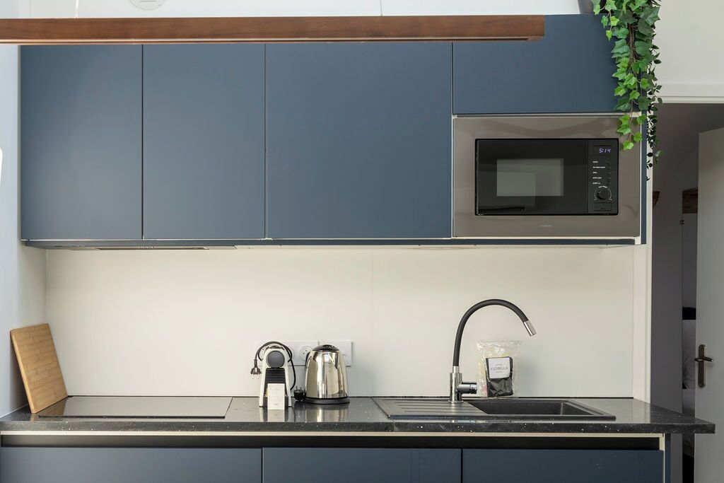 Una cucina moderna con forno a microonde, bollitore e lavello.