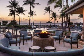 A resort pool area with lounge chairs, a fire pit, and palm trees. - Beachfront Lahaina Resort: Spacious 2BR Oasis, Full Access & Snorkeling (Lahaina)