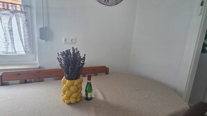 A dining area with a round wall clock, a table with a beige tablecloth, a bottle of wine, and a decorative plant. - Vacation Rental in the Heart of Gieselwerder (Wesertal)