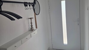 A hallway with a white door, a window, and a wall-mounted rack with hooks. - Vacation Rental in the Heart of Gieselwerder (Wesertal)