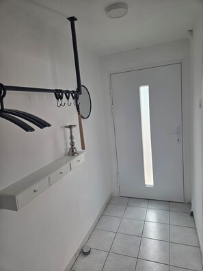 Un corridoio con una porta bianca, una finestra e un appendiabiti a parete.
