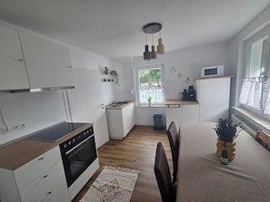 Cocina compacta con horno integrado, lavamanos y ventana con vistas al exterior.