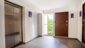 A hallway with a sliding door, a wooden door, and a view of greenery outside. - Luxury Beachfront | Corner Condo | Amazing Pools (Puerto Vallarta)