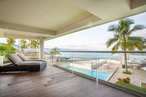 Ein Balkon mit Pool, Liegestühlen und Meerblick.