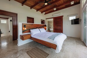 A bedroom with a wooden bed, a nightstand, a wall-mounted TV, and a stone accent wall.