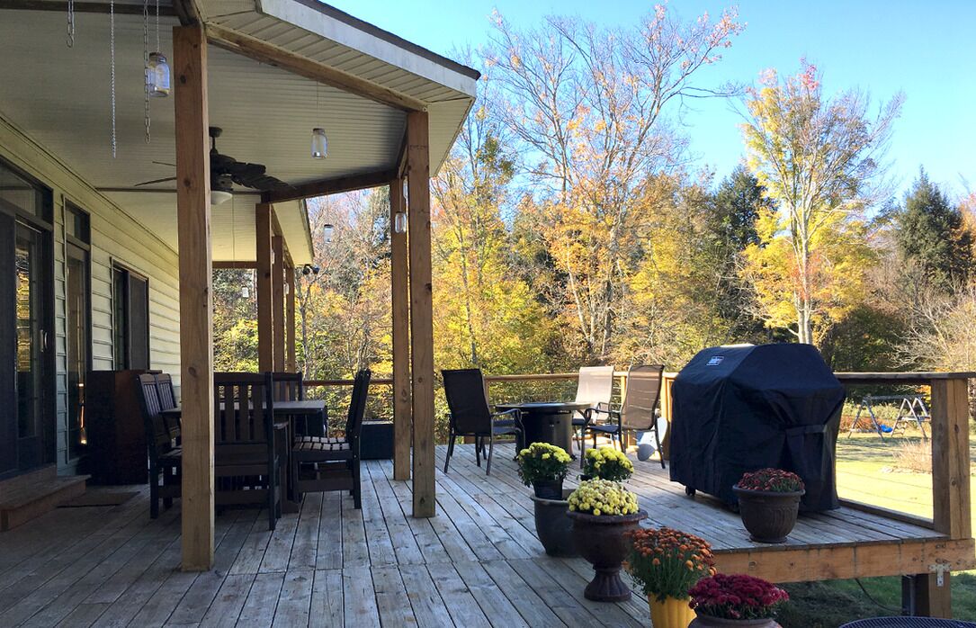 A wooden deck with outdoor furniture, a barbecue grill, and potted plants.