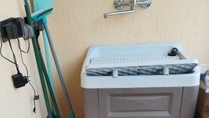 A bathroom with a grey cabinet, a shower area, and a wall-mounted faucet. - "Cozy, newly built villa just 5 minutes from the sea (Sardegna)