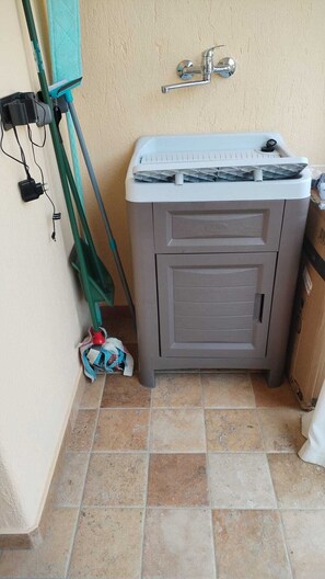 Ein Badezimmer mit grauem Schrank, einer Duschkabine und einem wandmontierten Wasserhahn.