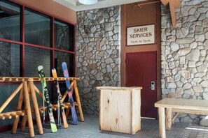 Un muro di pietra con un cartello che indica 'SKIER SERVICES' e una panchina di legno.