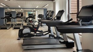 Ein Fitnessraum mit mehreren Laufbändern, Crosstrainern und einer Spiegelwand.