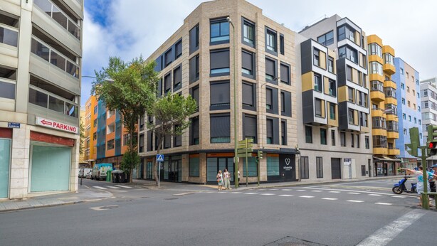 A multi-story building with a modern architectural design, featuring a mix of glass and brick facades. - Apartment in Las Palmas Near Playa Canteras (Las Palmas de Gran Canaria)