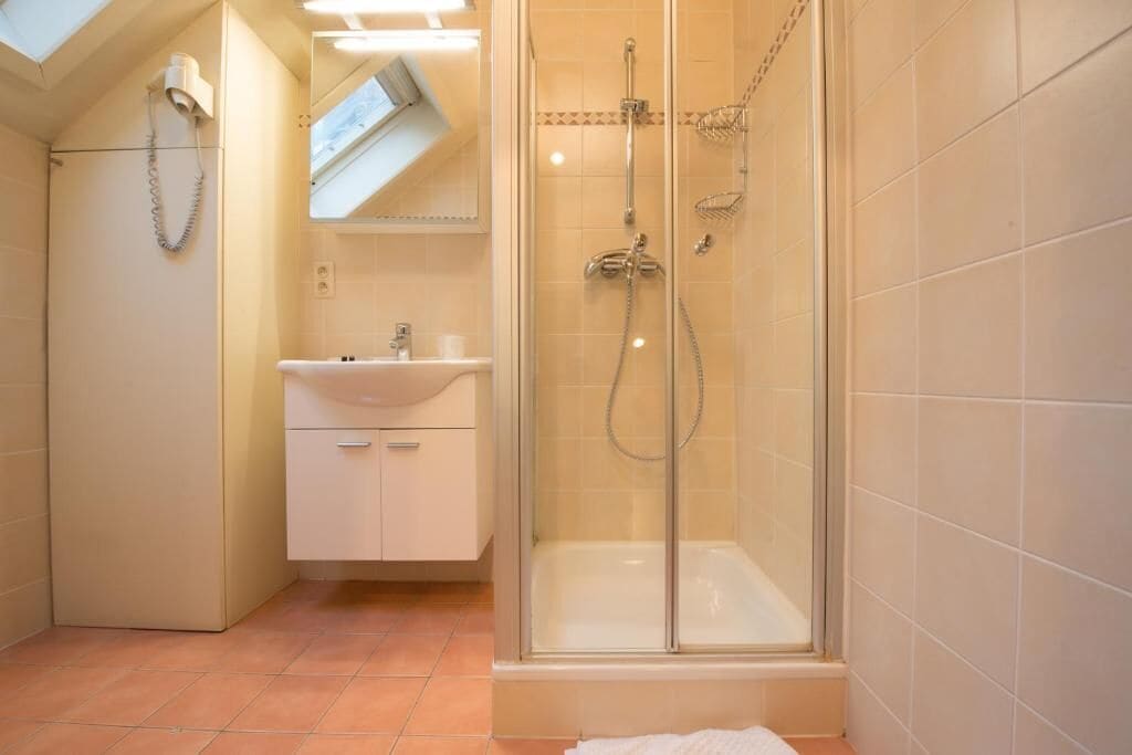 A bathroom with a glass-enclosed shower, a sink, and a mirror above it.