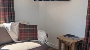 Een woonkamer met een bank, een voetenbankje en een kleine houten tafel met een tablet.