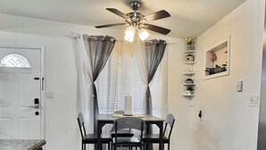 A compact kitchen with a dining table, chairs, a ceiling fan, and a white door. - Beautifully Renovated Home with Fenced Yard and Gazebo in a Prime Location (Pinellas Park)