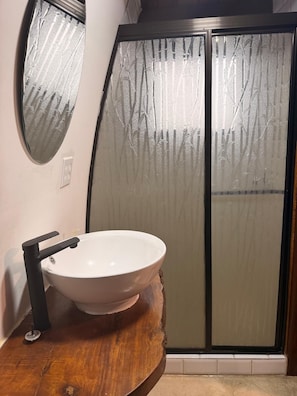 Ein Badezimmer mit einem weißen Waschbecken, einem schwarzen Wasserhahn und einem Holzkosmetikschrank.