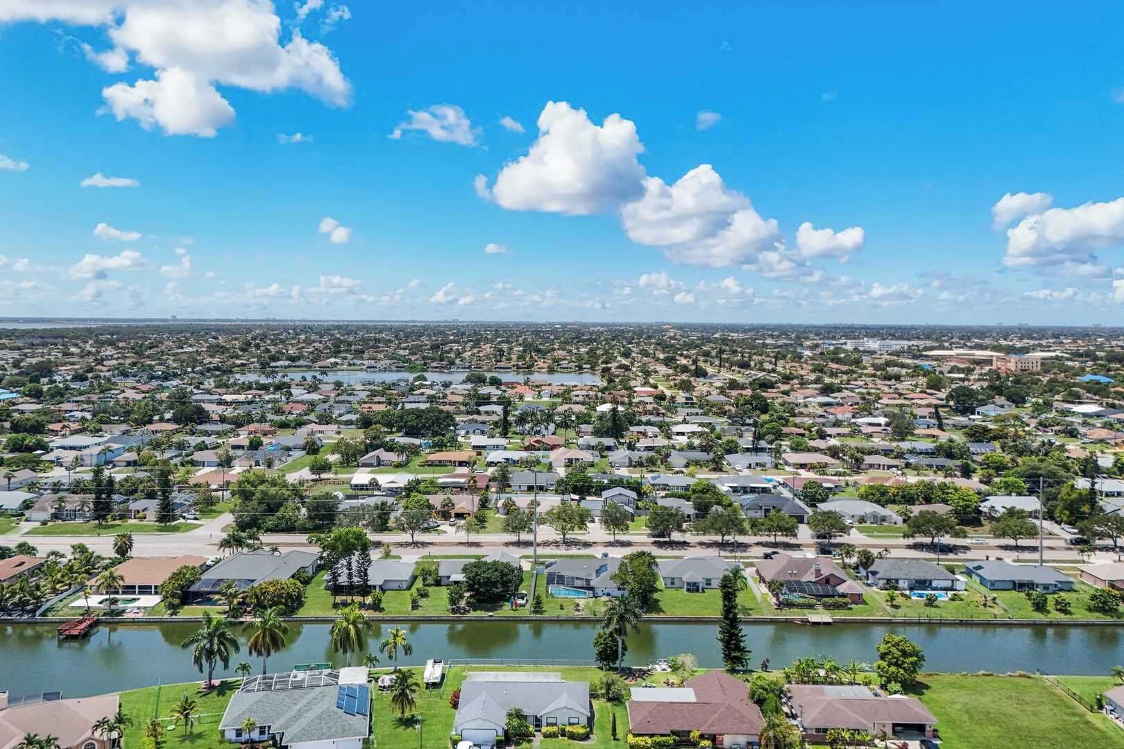A residential area with houses, a body of water, and a clear sky.