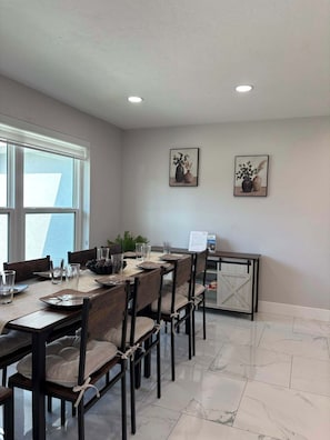 A dining area with a long table, chairs, and a view of the outdoors through large windows. - Villa Turtle View right on the water (Cape Coral)