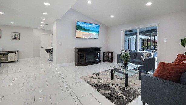 A modern living room with a fireplace, a flat-screen TV, and a sofa. - Villa Turtle View right on the water (Cape Coral)