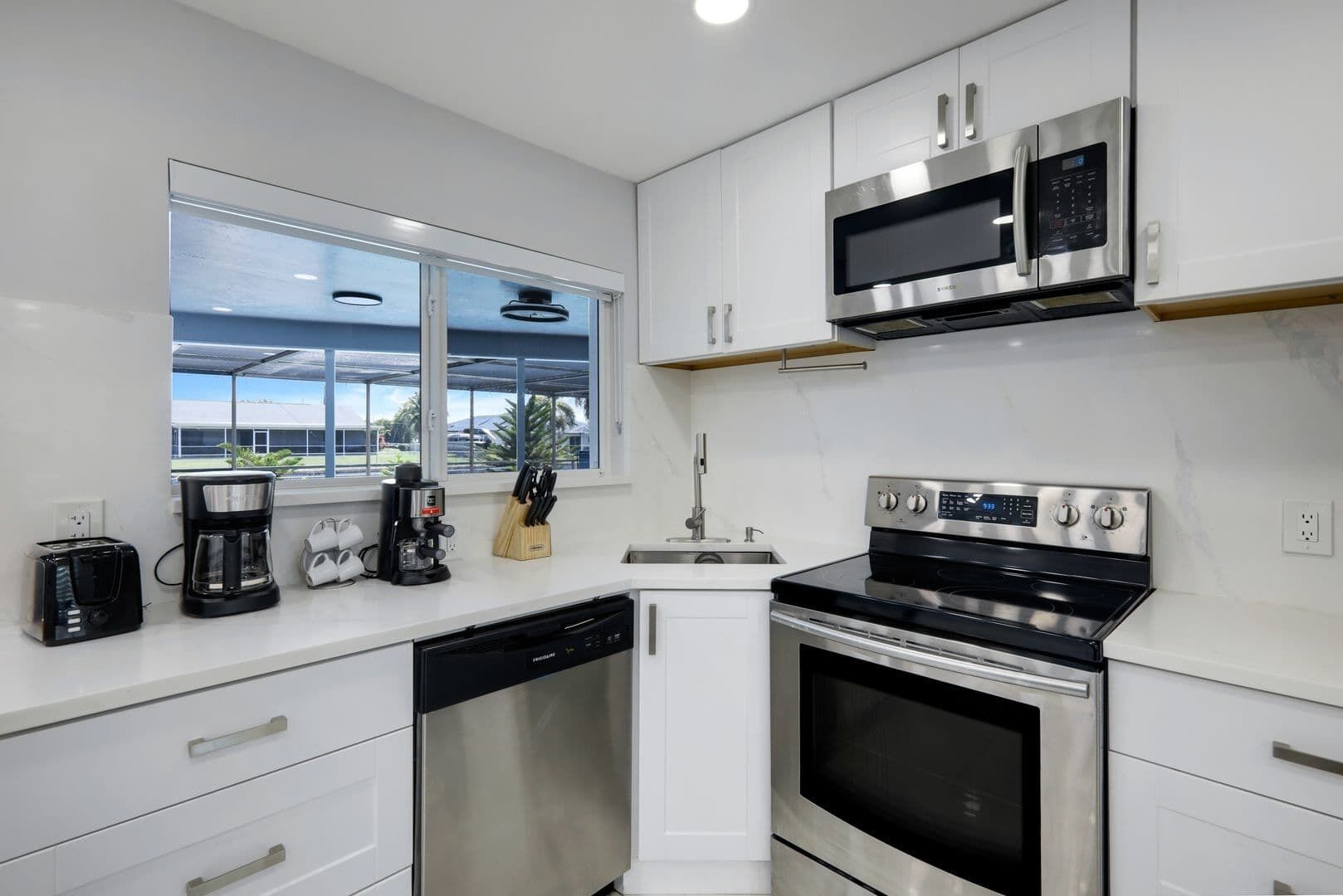 A modern kitchen with white cabinetry, a built-in dishwasher, a stove, and a microwave.